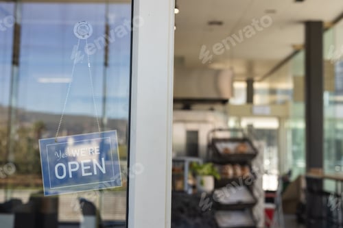 Preview: Yes WE'RE OPEN sign is hanging on glass door with dotted chain, blurred bakery interior