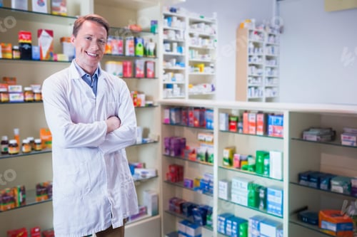 Preview: Male pharmacist wearing white lab coat standing by pharmacy shelves with pill bottles, copy space