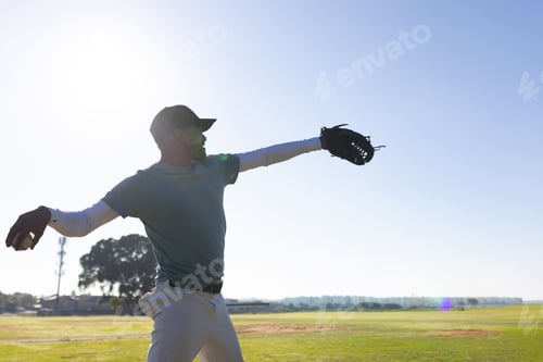 Preview: Baseball player is reaching with leather glove on grassy field under bright sun, copy space