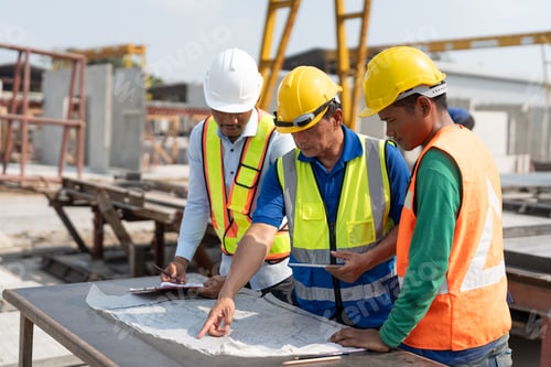 Preview: Asian senior engineer foreman and workers review blueprint at construction site