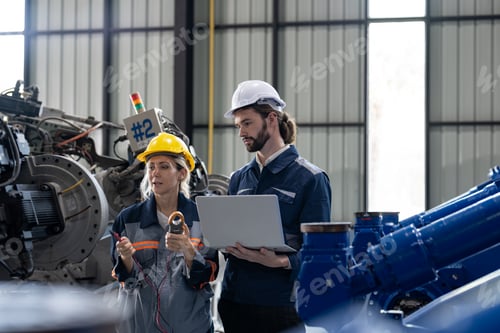 Preview: Male and female engineers with laptop checking maintaining robot arm welding machine at factory