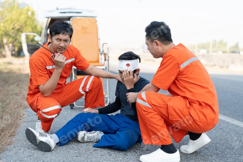 Preview: Asian male ems paramedics orange uniforms performing first aid to patient with road accident injury