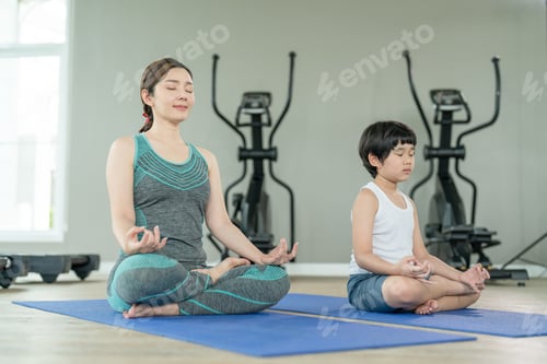 Preview: Happy Asian mother and son wearing sportswear practices yoga together in small gym sports club