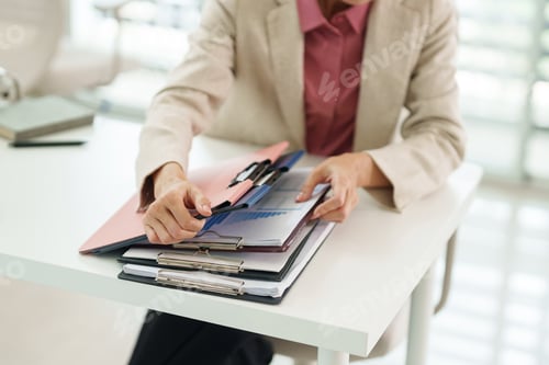 Preview: Professional adult arranges business documents meticulously sorting financial reports administrative