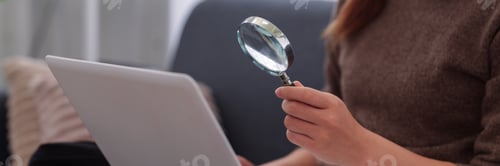 Preview: Business Professional Using Magnifying Glass Analyzing Information on Laptop Computer Researching Da