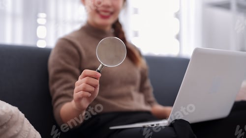Preview: Asian business women holding magnifying glass using laptop computer for research analysis data inves