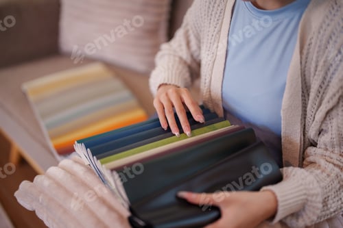Preview: Woman choosing fabric swatches for furniture design at home interior