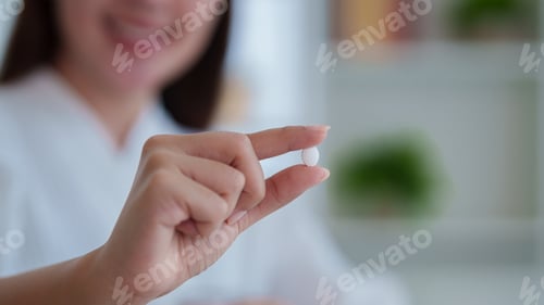 Preview: Asian women hand holding white pill tablet medicine supplement vitamin for health wellness treatment