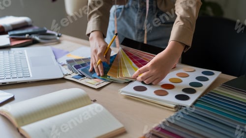 Preview: Fashion designer selecting color palette from swatches while working on creative project at studio d