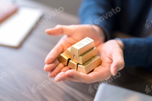 Preview: Business professional holding stack of gold bars symbolizing wealth investment and financial securit