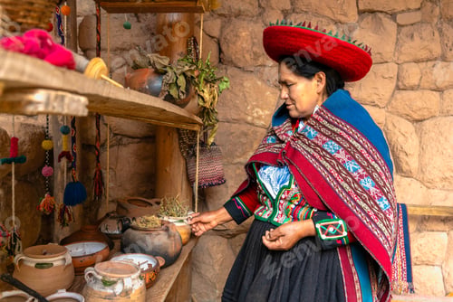 Preview: Peruvian woman wearing traditional clothing examining traditional woven goods on shelves indoors