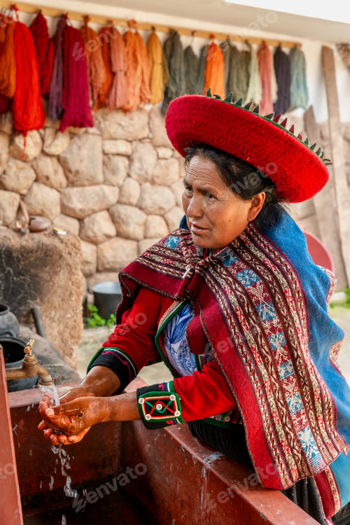 Preview: Peruvian woman washing hands in rustic village courtyard with colorful wool background