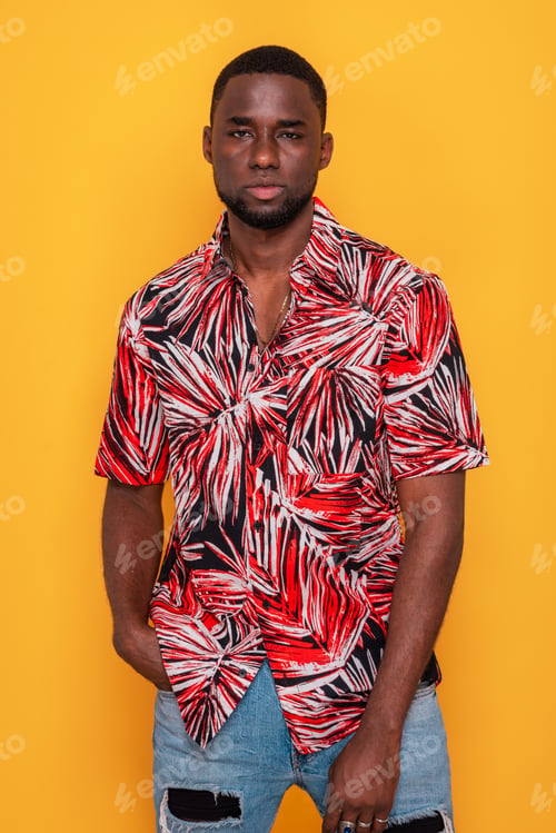 Preview: Young African American man in red tropical shirt posing on yellow background