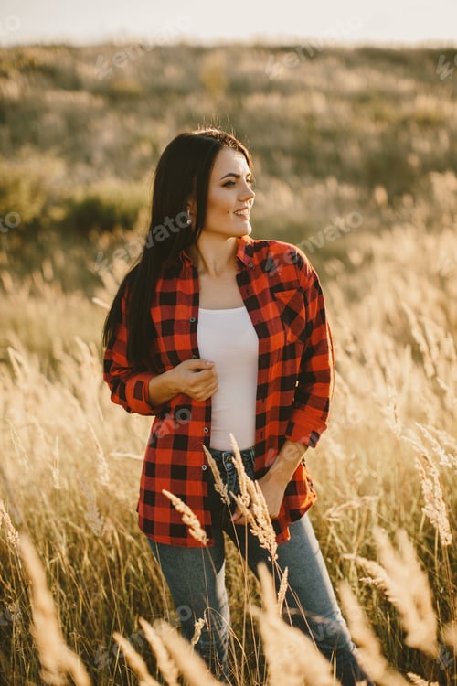 Preview: Smiling Woman in Red Plaid Shirt Standing in Sunny Grass Field