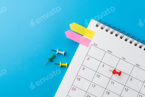 Preview: A top-down view of a spiral desk calendar with colorful arrow sticky notes and push pins.