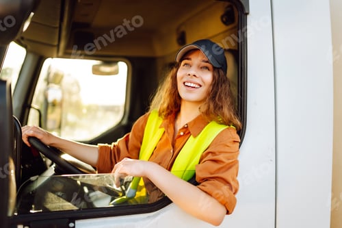 Preview: Portrait of beautiful young woman professional truck driver driving a big truck. Inside of vehicle