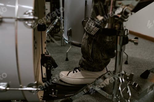 Preview: Close up of teenager drummer pressing bass pedal during practice on drum kit, showing music learning