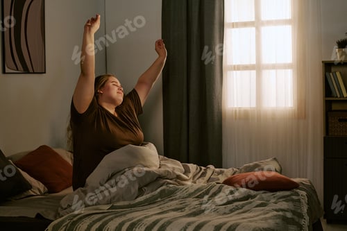 Preview: Plus Size Woman Stretching in Bed during Morning Wellness Routine