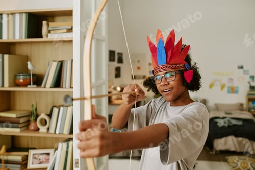 Preview: Black Child Wearing Costume and Playing Archer at Home