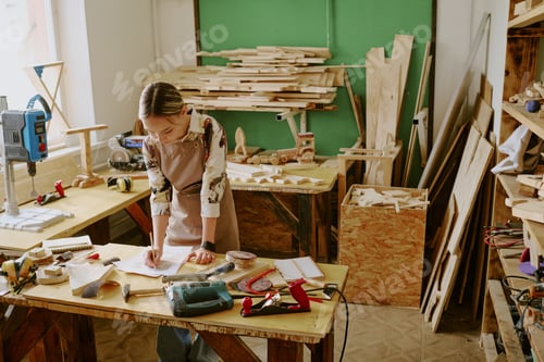 Preview: Teenage Girl Sketching Woodworking Project in Carpentry Workshop