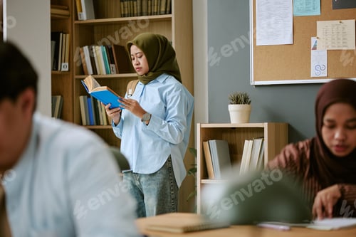 Preview: Adult Asian Woman Reading Book in Classroom for Migrant Education