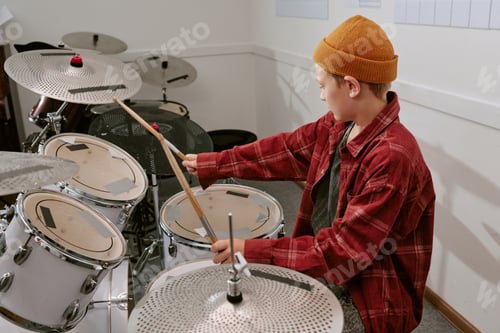 Preview: Caucasian boy playing drum kit during music lesson, practicing rhythm and coordination in rehearsal
