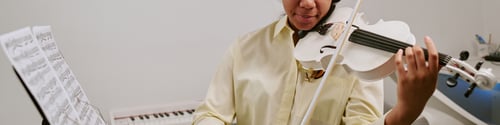 Preview: Website banner of teenager playing drum kit while adult instructor guiding hand position during musi