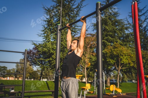 Preview: One man muscular male athlete training pull ups outdoor in sunny day