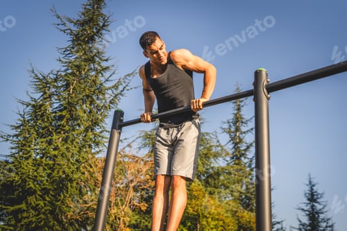 Preview: One man muscular male athlete training pull ups outdoor in sunny day