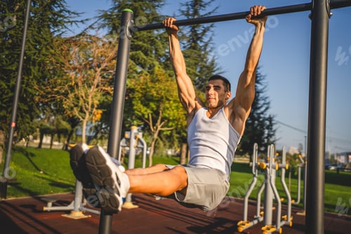 Preview: One man muscular male athlete training pull ups outdoor in sunny day