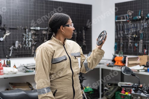 Preview: Woman mechanic examining gear in a workshop