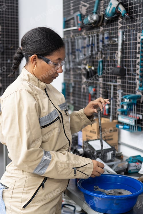 Preview: Black woman engineer working and cleaning metal parts