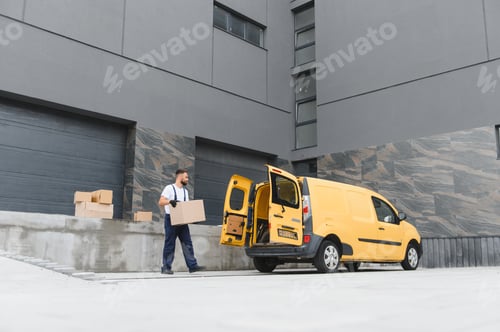Preview: Courier carrying cardboard box to delivery van outside warehouse