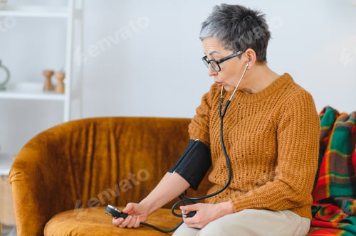 Preview: Senior woman monitoring blood pressure checking health at home