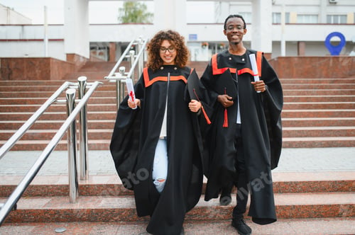 Preview: Graduates walking down stairs holding diplomas