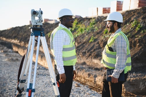 Preview: Diverse land surveyors discussing project at road construction site