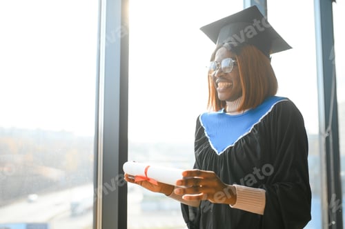 Preview: Portrait of African American graduate student in toga holding her diploma