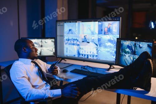 Preview: African American security officer or dispatch uses computer and walkie talkie, looks at screens