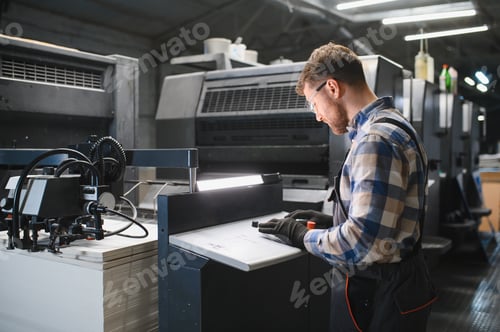Preview: Worker operating industrial printing machine in factory
