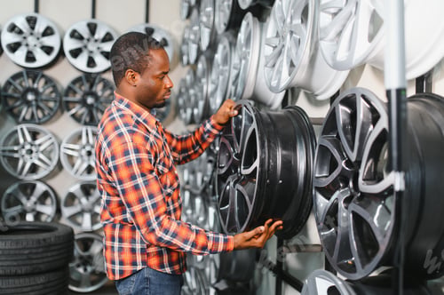 Preview: African american male customer choosing alloy wheel rims at car repair service or auto store