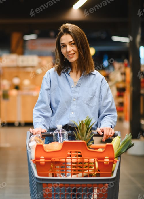 Preview: Young woman shopping for groceries in supermarket aisle