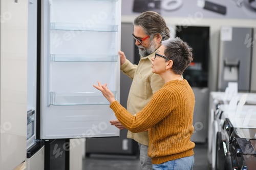 Preview: Mature couple choosing new refrigerator in appliance store