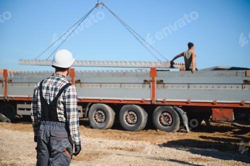 Preview: A builder controls a crane while unloading panels to cover a house