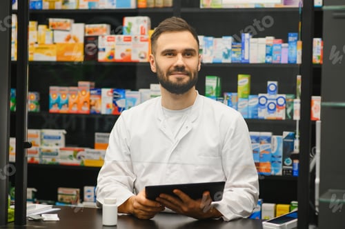 Preview: Male pharmacist using tablet in modern pharmacy