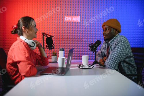 Preview: Two Radio Hosts in Headphones Laughing While Recording Podcast in Studio Together