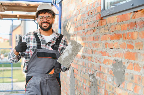 Preview: Happy construction worker giving thumbs up next to brick wall