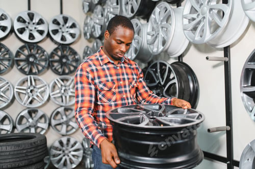 Preview: African american male customer choosing alloy wheel rims at car repair service or auto store