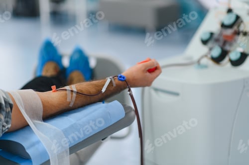 Preview: Person donating blood using apheresis machine