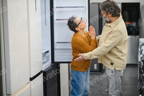 Preview: Mature couple choosing new refrigerator in appliance store