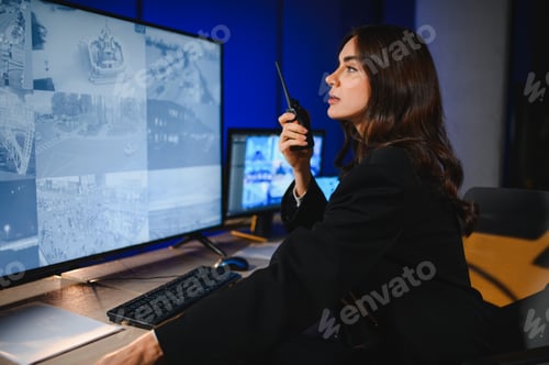 Preview: Woman security operator monitoring surveillance cameras at night